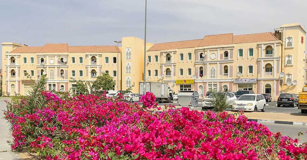 A vibrant view of International City Dubai, featuring unique residential buildings and a bustling community atmosphere under a clear blue sky.