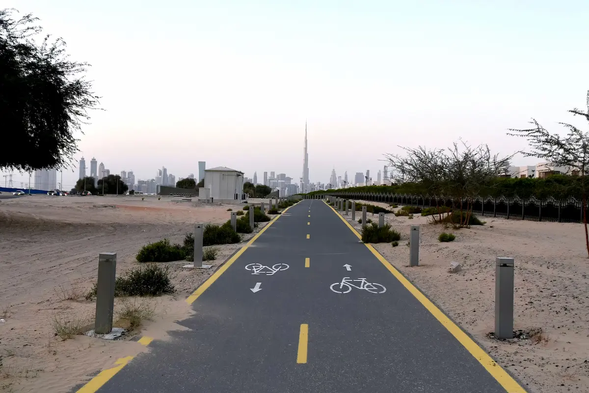 A scenic view of Nad Al Sheba Cycle Park in Dubai, featuring a smooth cycling track surrounded by greenery under a clear blue sky.