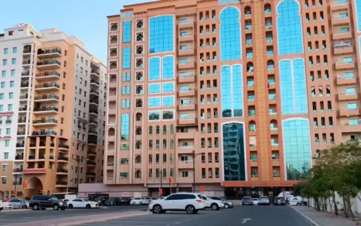 A scenic view of Al Nahda 2 Dubai featuring modern residential buildings, lush green parks, and well-maintained apartment complexes under a clear blue sky.